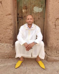 abdelkarim sitting in a Marrakech doorway in yellow leather babouche shoes