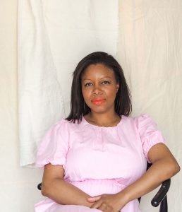 jane badu owner of we are nomads in a pink dress sitting on a chair nomads