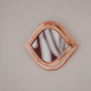 a copper framed mirror fixed to a wall