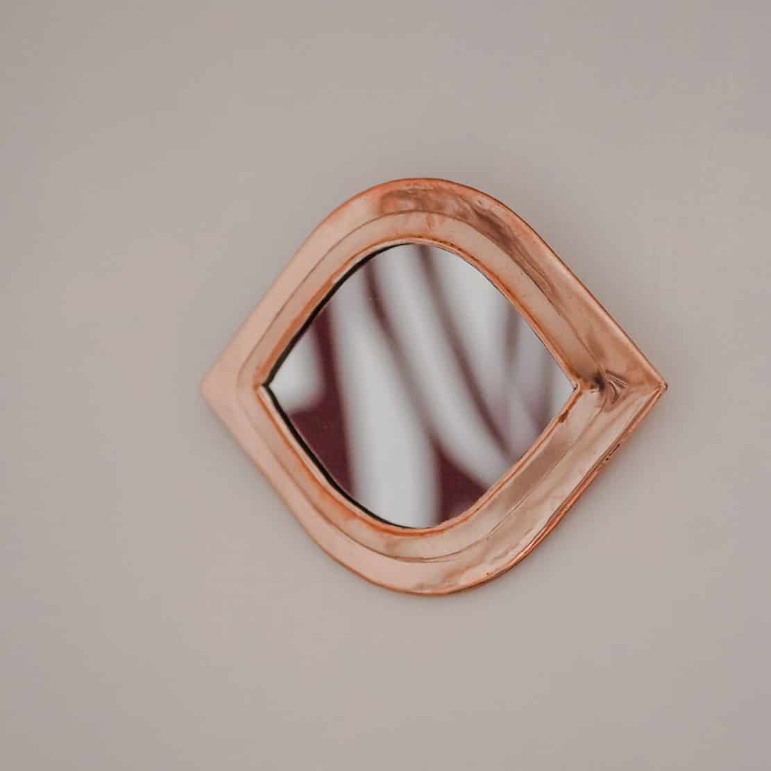 a copper framed mirror fixed to a wall