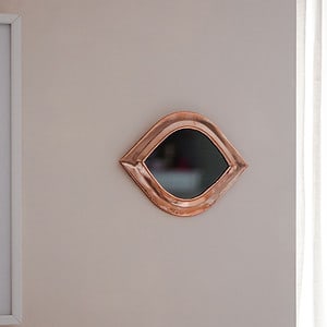 a moroccan made small mirror with a copper frame fixed to a wall