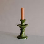 small green ceramic candlestick with an orange st eval candle in