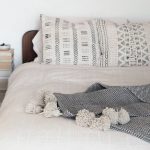 A bedroom with a white duvet cover and Mali print cushions