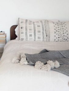 A bedroom with a white duvet cover and Mali print cushions
