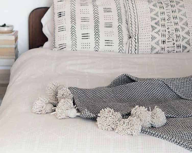 A bedroom with a white duvet cover and Mali print cushions