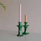 two green tamegroute candlesticks on marble backdrop holding a pink and an orange dinner candles