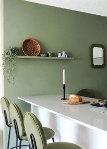 Sage green painted wall in a modern kitchen with white cabinets and a marble top