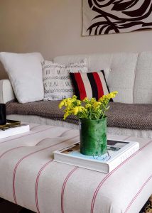 image of the interior design of a lounge woth a white sofa and striped footstool in chorlton manchester
