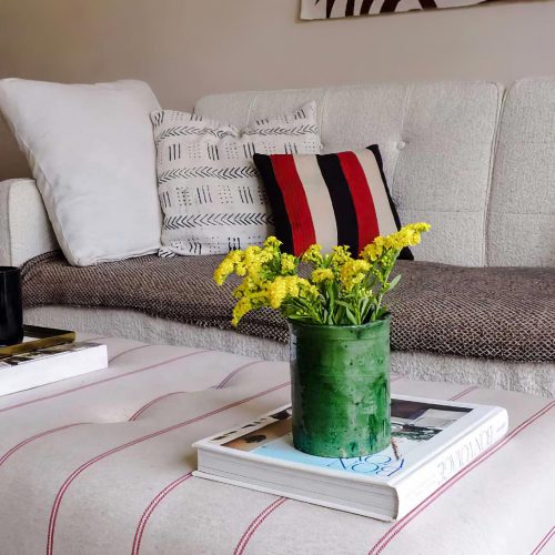 image of the interior design of a lounge woth a white sofa and striped footstool in chorlton manchester