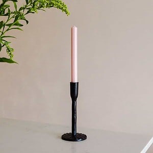 black iron candlestick holding a rose pink dinner candle by st eval we are nomads